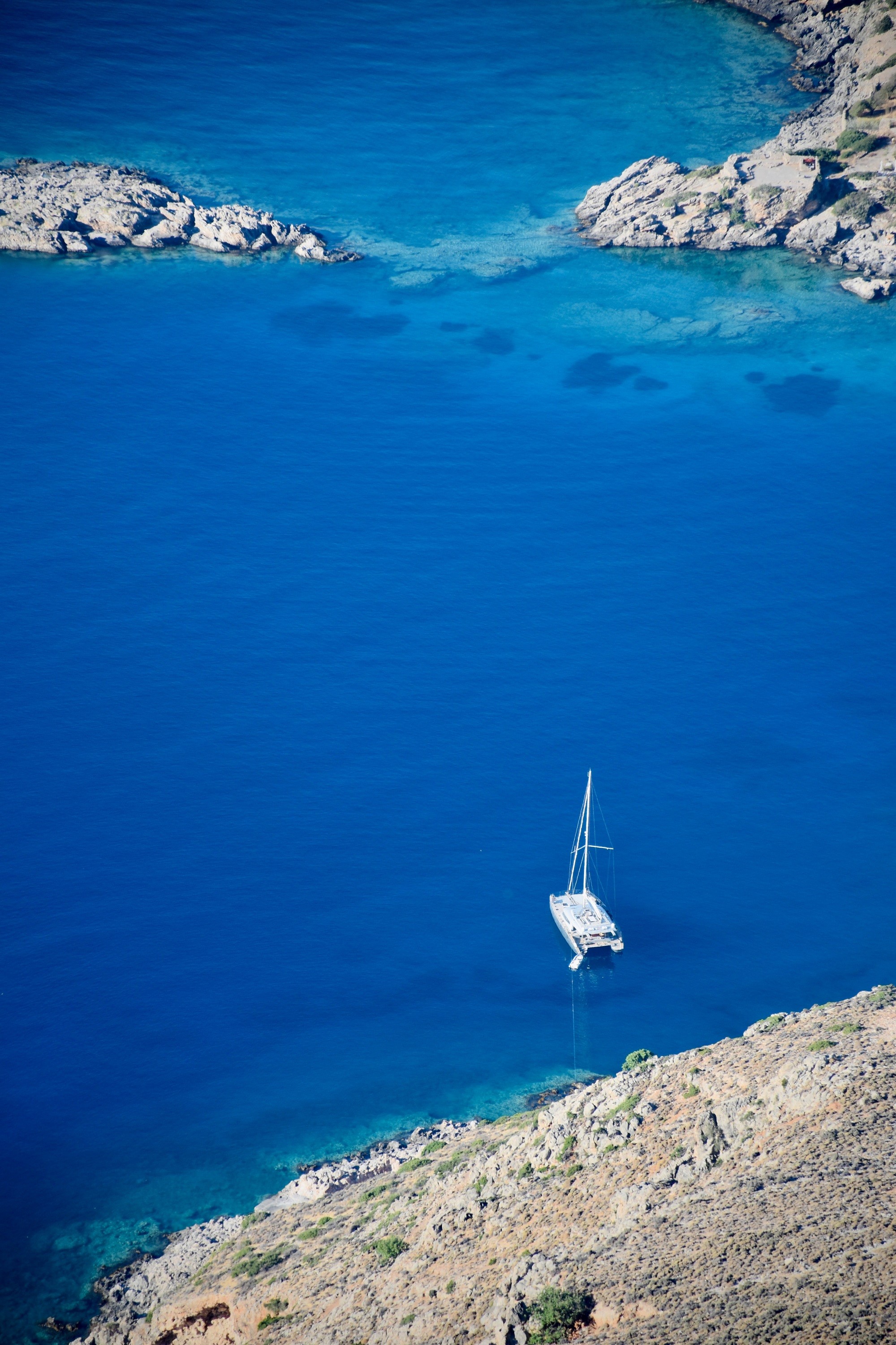 Lone sailing boat in southern crete seen from high up in the highlands